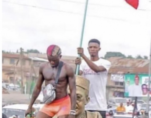 Portable strips to his boxers in front of a statue of Obafemi Awolowo, as he campaigns for APC